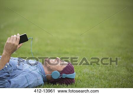 Man listening to headphones on lawn View Large Photo Image Stock Image - Man listening to headphones on lawn. Fotosearch