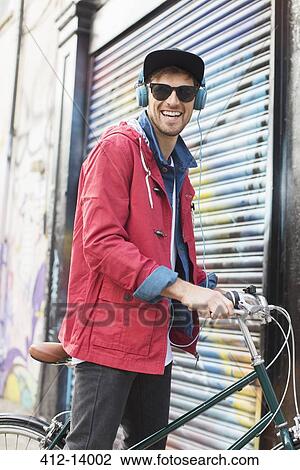 Stock Image - Man pushing bicycle on city street. Fotosearch