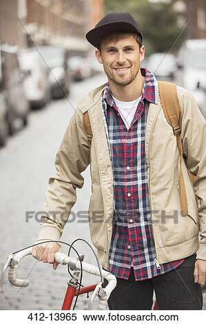 Stock Photography - Man pushing bicycle on city street. Fotosearch