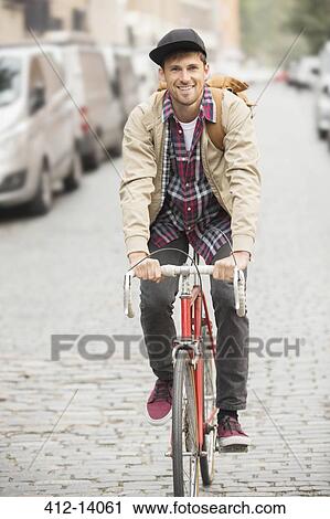 Man riding bicycle on city street View Large Photo Image Stock Image - Man riding bicycle on city street. Fotosearch