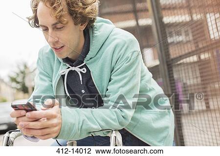 Stock Image - Man using cell phone on bicycle. Fotosearch