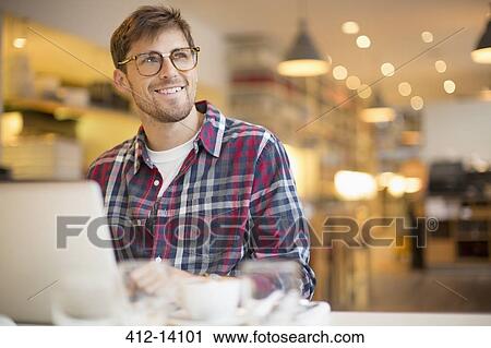 Stock Image - Man using laptop in cafe. Fotosearch