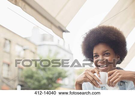 Stock Image - Woman drinking coffee at sidewalk cafe. Fotosearch