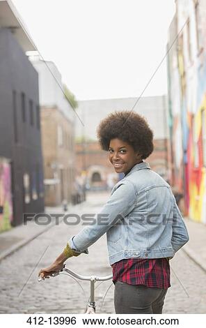 Stock Photograph - Woman pushing bicycle on city street. Fotosearch