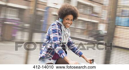Stock Image - Woman riding bicycle on city street. Fotosearch