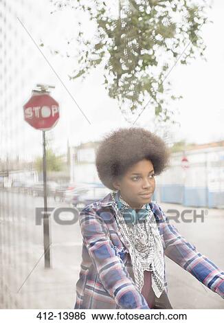 Stock Photograph - Woman riding bicycle on city street. Fotosearch