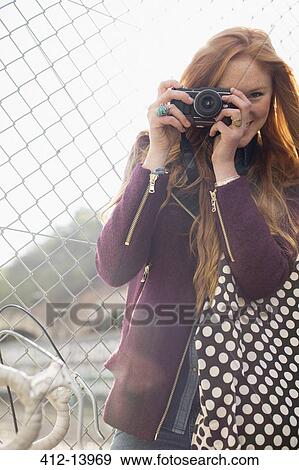 Woman smiling by chain link fence View Large Photo Image Stock Photo - Woman smiling by chain link fence. Fotosearch