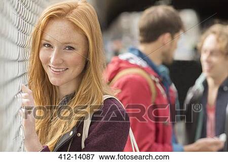 Woman smiling by chain link fence View Large Photo Image Stock Photo - Woman smiling by chain link fence. Fotosearch