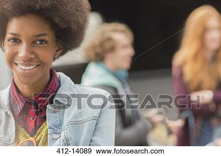 Woman smiling with friends in background View Large Photo Image Stock Photo - Woman smiling with friends in background. Fotosearch