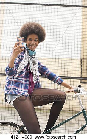 Stock Image - Woman taking self-portrait on bicycle. Fotosearch