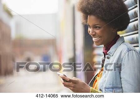 Stock Photography - Woman using cell phone on city street. Fotosearch
