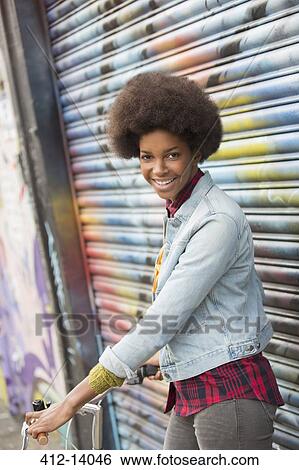 Stock Photograph - Woman with bicycle in front of graffiti wall. Fotosearch