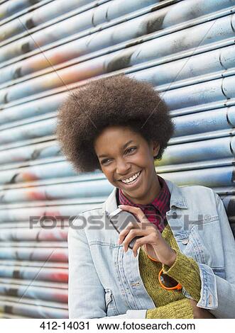 Woman with cell phone smiling against graffiti wall View Large Photo Image Stock Image - Woman with cell phone smiling against graffiti wall. Fotosearch