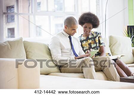 Stock Image - Business people using digital tablet on sofa. Fotosearch