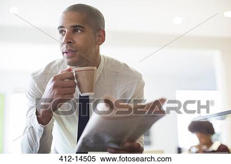 Stock Photography - Businessman reading newspaper and drinking coffee. Fotosearch