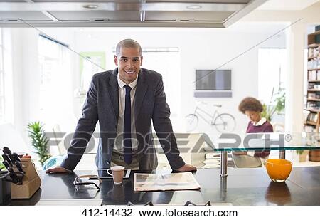Stock Image - Businessman reading newspaper at table. Fotosearch