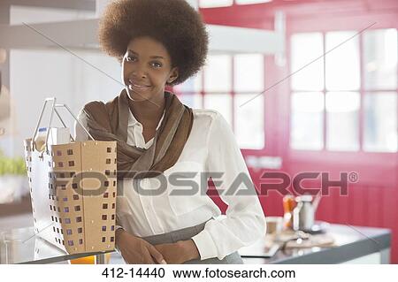 Stock Image - Businesswoman smiling in kitchen. Fotosearch