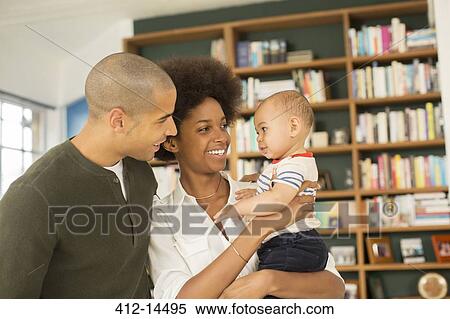 Couple holding baby in living room View Large Photo Image Stock Photography - Couple holding baby in living room. Fotosearch