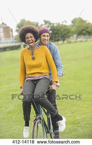 Couple riding bicycle together in park View Large Photo Image Stock Photo - Couple riding bicycle together in park. Fotosearch
