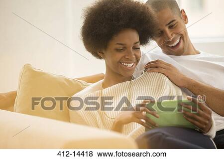 Stock Photo - Couple using digital tablet on sofa. Fotosearch