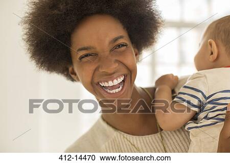 Stock Image - Laughing mother holding baby boy. Fotosearch