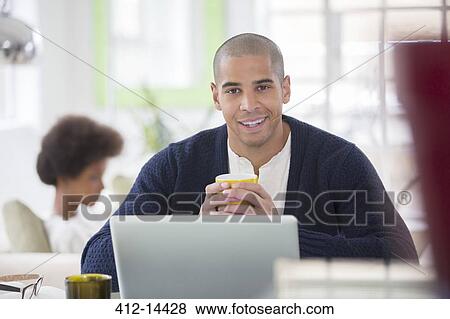 Stock Photo - Man using laptop at table. Fotosearch