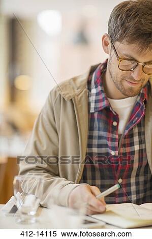 Stock Photography - Man writing in cafe. Fotosearch