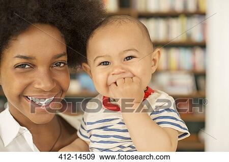 Mother holding baby boy in living room View Large Photo Image Stock Photo - Mother holding baby boy in living room. Fotosearch