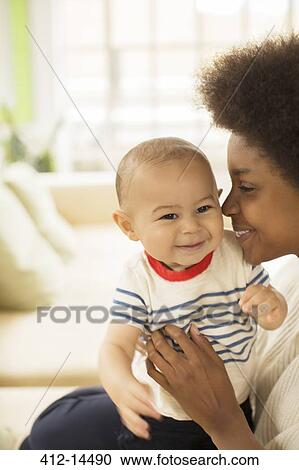 Mother holding baby boy on sofa View Large Photo Image Stock Image - Mother holding baby boy on sofa. Fotosearch