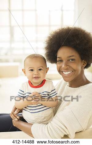 Mother holding baby boy on sofa View Large Photo Image Stock Photo - Mother holding baby boy on sofa. Fotosearch