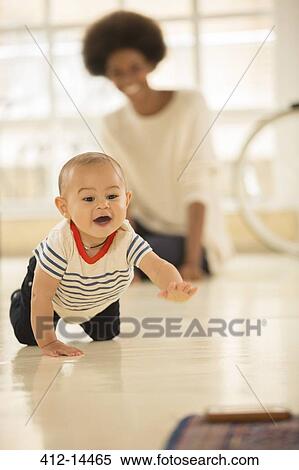Stock Photography - Mother watching baby boy crawl on floor. Fotosearch