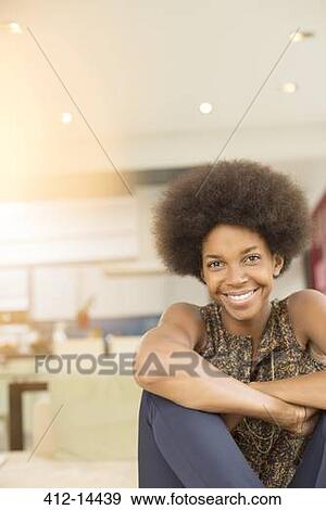 Smiling woman sitting in living room View Large Photo Image Stock Photo - Smiling woman sitting in living room. Fotosearch