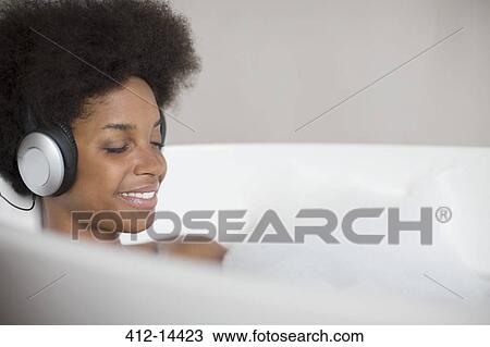 Woman listening to headphones in bath View Large Photo Image Stock Image - Woman listening to headphones in bath. Fotosearch