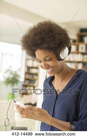 Woman listening to headphones in living room View Large Photo Image Stock Photo - Woman listening to headphones in living room. Fotosearch