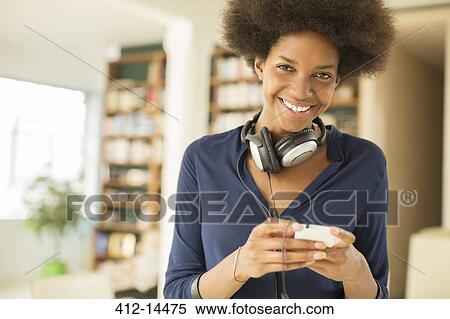 Stock Photography - Woman listening to headphones in living room. Fotosearch