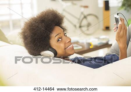 Woman listening to headphones on sofa View Large Photo Image Picture - Woman listening to headphones on sofa. Fotosearch