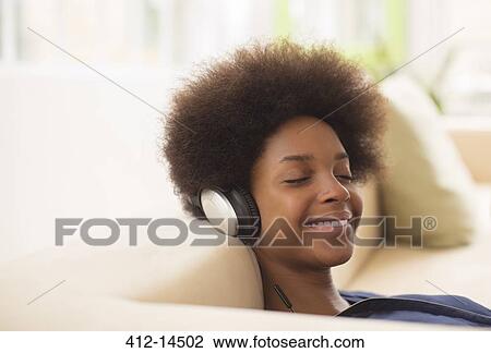 Woman listening to headphones on sofa View Large Photo Image Stock Image - Woman listening to headphones on sofa. Fotosearch