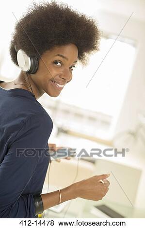 Woman listening to headphones on sofa View Large Photo Image Stock Photo - Woman listening to headphones on sofa. Fotosearch