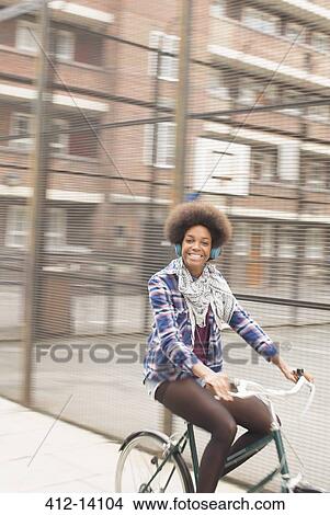 Picture - Woman riding bicycle on city street. Fotosearch