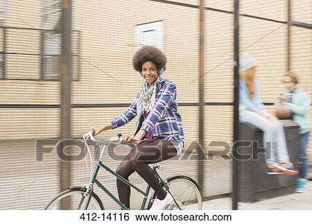 Woman riding bicycle on city street View Large Photo Image Stock Photograph - Woman riding bicycle on city street. Fotosearch