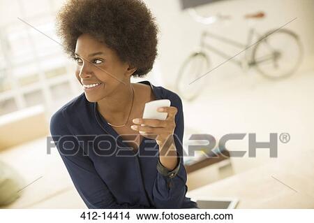 Woman using cell phone in living room View Large Photo Image Picture - Woman using cell phone in living room. Fotosearch