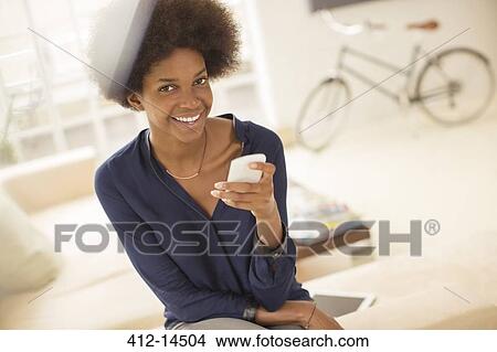Woman using cell phone in living room View Large Photo Image Picture - Woman using cell phone in living room. Fotosearch