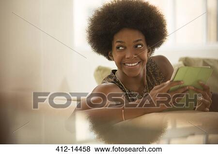 Woman using digital tablet on sofa View Large Photo Image Stock Photo - Woman using digital tablet on sofa. Fotosearch