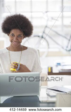Stock Photo - Woman using laptop at desk. Fotosearch