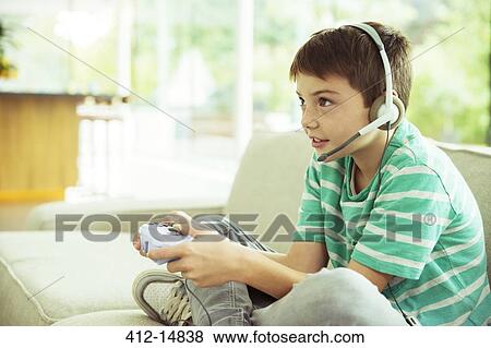 Boy playing video games on sofa View Large Photo Image Stock Photo - Boy playing video games on sofa. Fotosearch