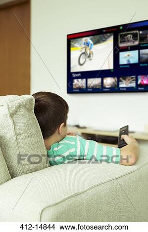 Boy watching television in living room View Large Photo Image Picture - Boy watching television in living room. Fotosearch