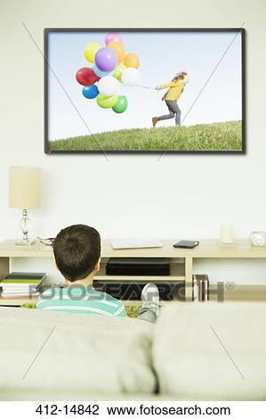 Boy watching television in living room View Large Photo Image Stock Image - Boy watching television in living room. Fotosearch