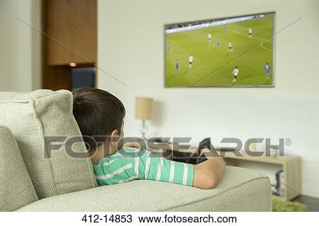 Boy watching television in living room View Large Photo Image Stock Image - Boy watching television in living room. Fotosearch