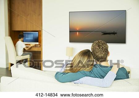 Picture - Couple watching television in living room. Fotosearch