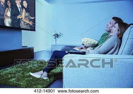 Couple watching television in living room View Large Photo Image Stock Image - Couple watching television in living room. Fotosearch